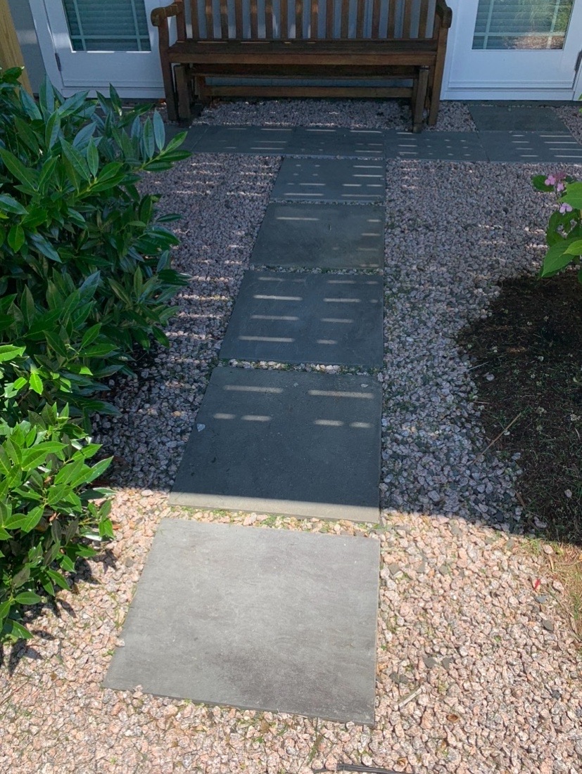 Bluestone slab walkway set in pea gravel leading to a backyard bench